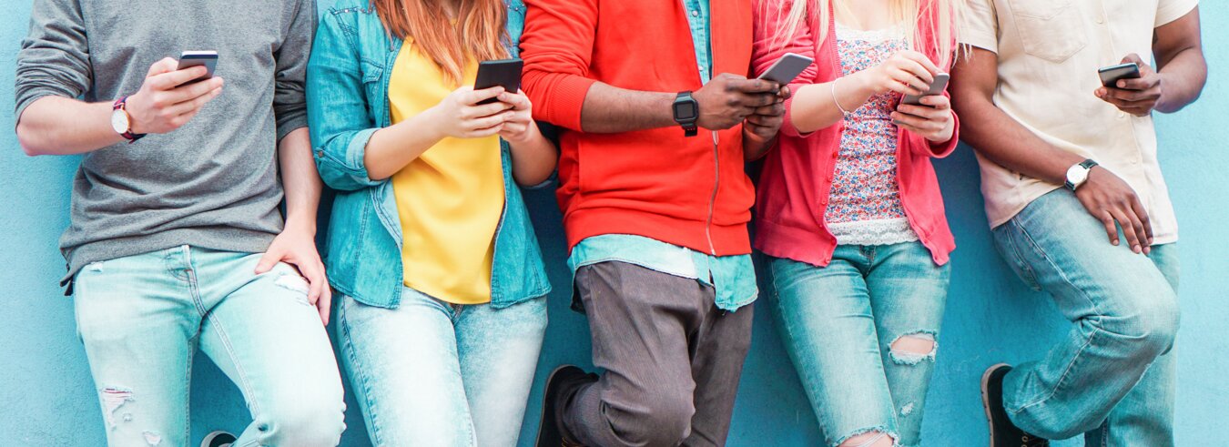Fünf Jugendliche stehen nebeneinander, jeder mit einem Handy in der Hand | © iStock.com/DisobeyArt